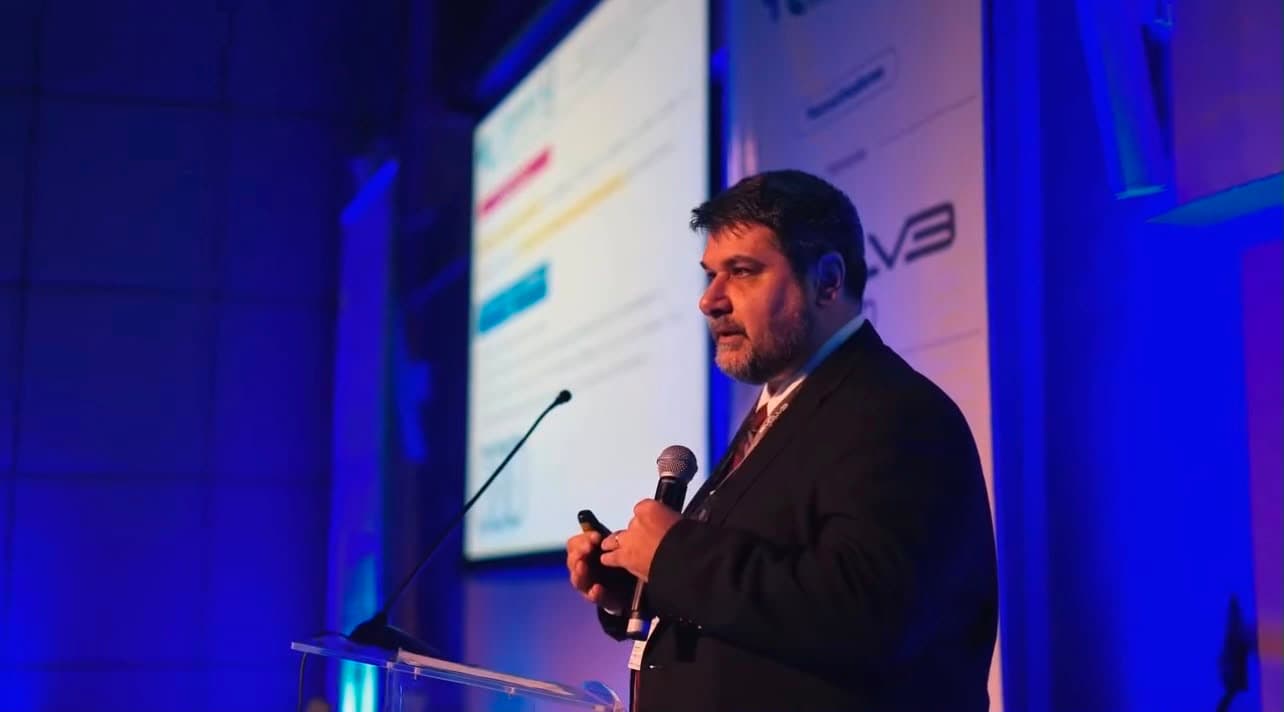 Palestrante apresentando um caso ao lado do slide projetado